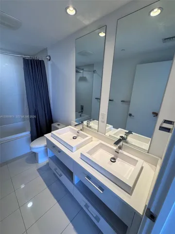 Floating vanity with dual rectangular vessel sinks, light-toned cabinetry, polished chrome faucets, large frameless mirrors, and tile flooring