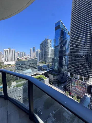 Private balcony with glass railing, stone-finish flooring, and expansive urban scenery