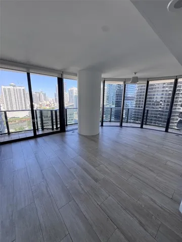 Floor-to-ceiling windows, wood-finish flooring, central structural column, and expansive balcony access