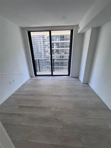 Interior space featuring wood-finish flooring, floor-to-ceiling sliding glass doors, and access to an exterior balcony