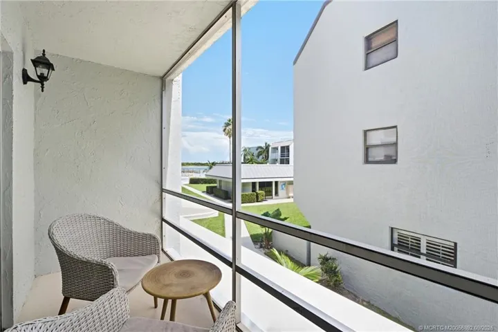 Private screened balcony offers a relaxing outdoor space with views toward the community grounds, pool, and water.