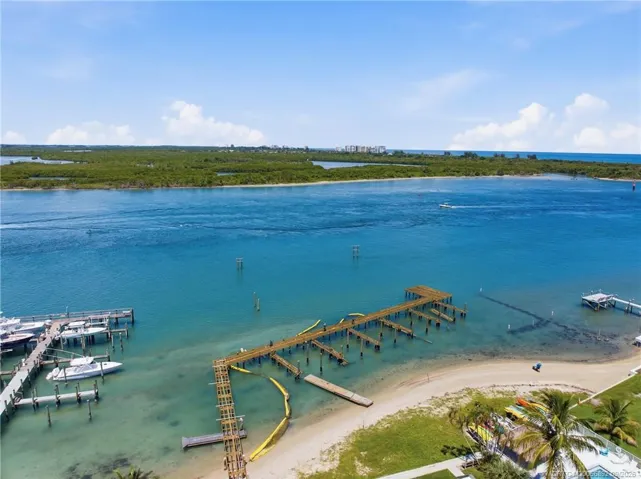 Aerial view showcasing the community’s waterfront setting, sandy shoreline, and dock area - currently under construction.
