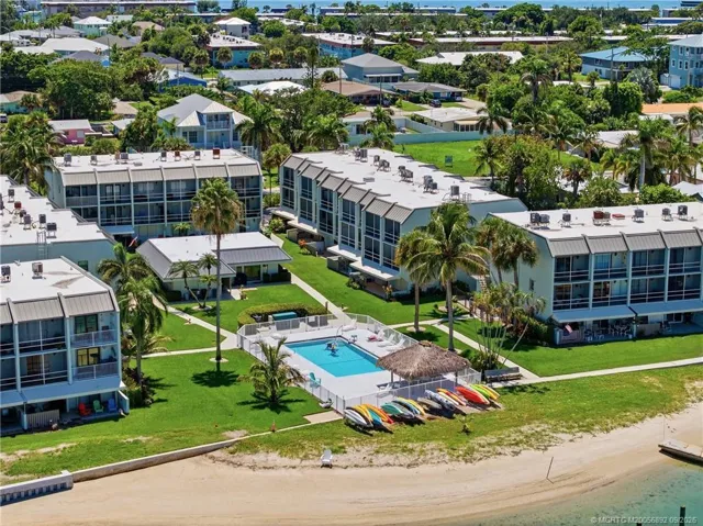 Closer aerial view of the community pool, waterfront grounds, sandy shoreline, and kayak storage.