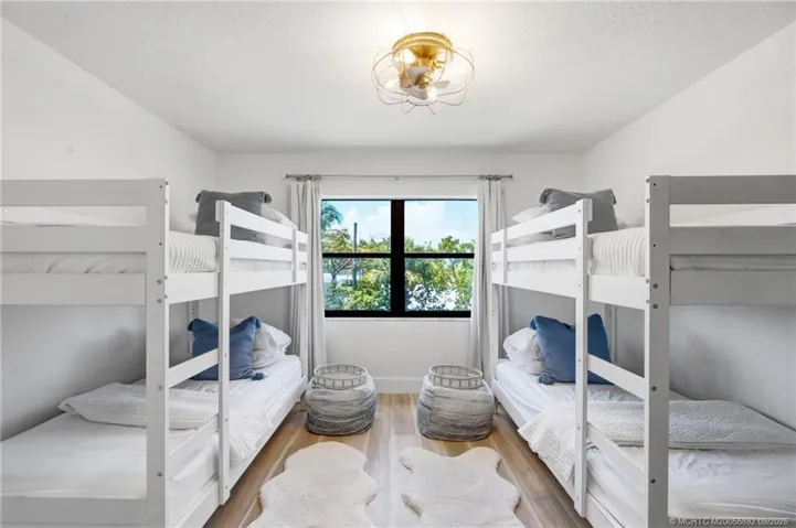 Generously sized guest bedroom offers flexible sleeping accommodations and a large window overlooking the tropical surroundings.