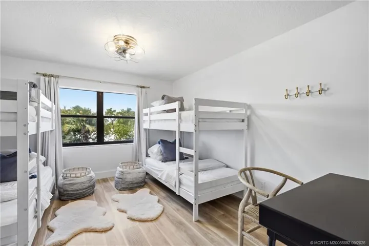 A second view showcases the room’s spacious layout, wood-look flooring, and additional space for a desk or workspace.