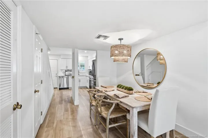 Spacious dining area connects directly to the kitchen and living room, complemented by wood-look flooring and a statement light fixture.