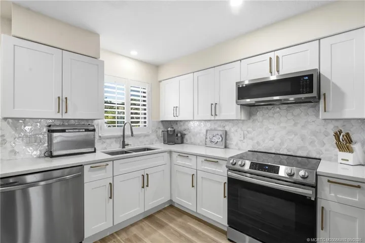 A closer view highlights abundant cabinetry and counter space, stainless steel appliances, and a window over the sink for natural light.