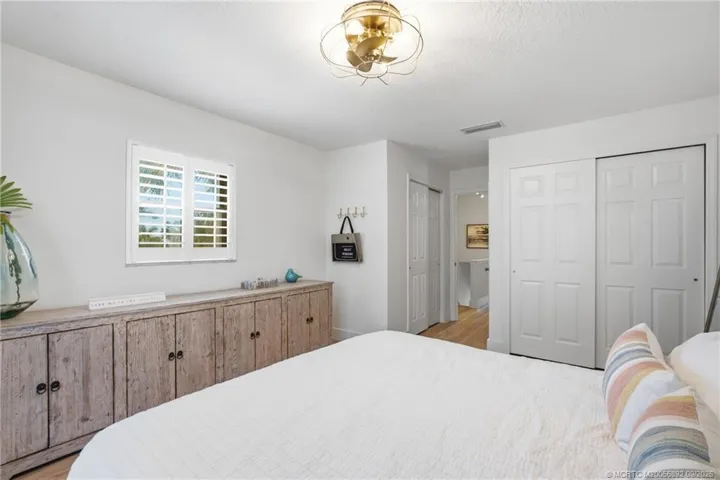 Another view of the primary bedroom highlights generous closet space, plantation shutters, and a clean coastal design.