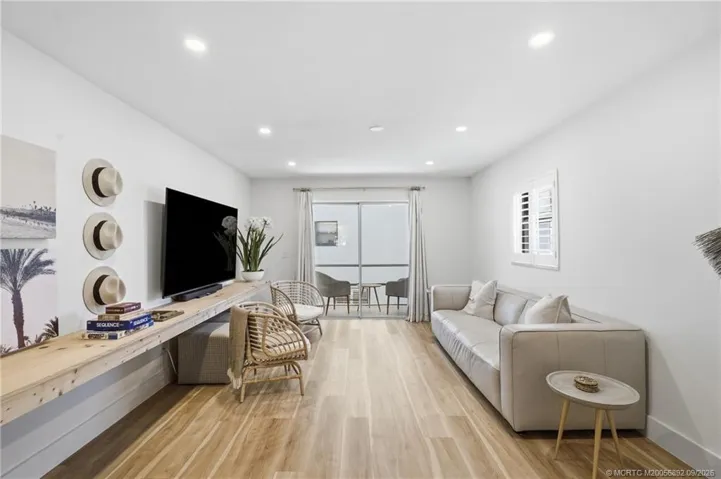 Generously sized living room features recessed lighting, wood-look flooring, and sliding glass doors leading to the outdoor space.