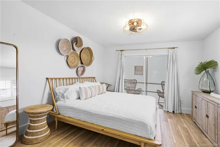 Spacious primary bedroom features wood-look flooring and sliding glass doors that open to a private outdoor space.