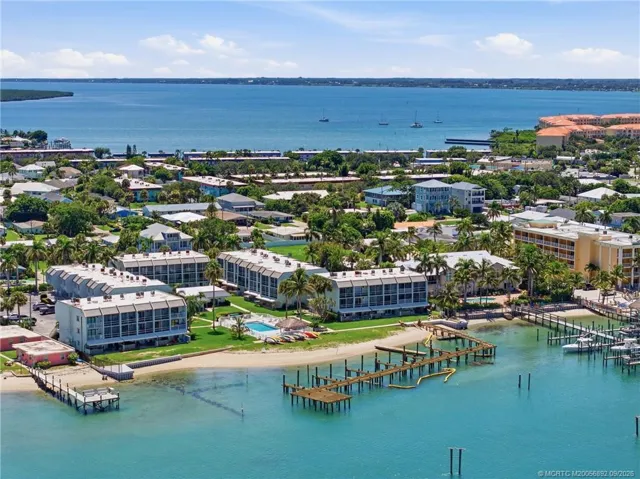 Closer aerial view showcases the community’s waterfront buildings, pool, shoreline, and dock area.