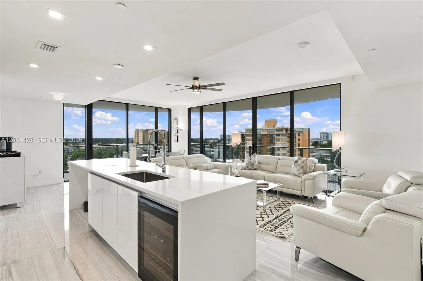 Open-concept kitchen with waterfall island, wine/beverage refrigerator, and adjoining living area.