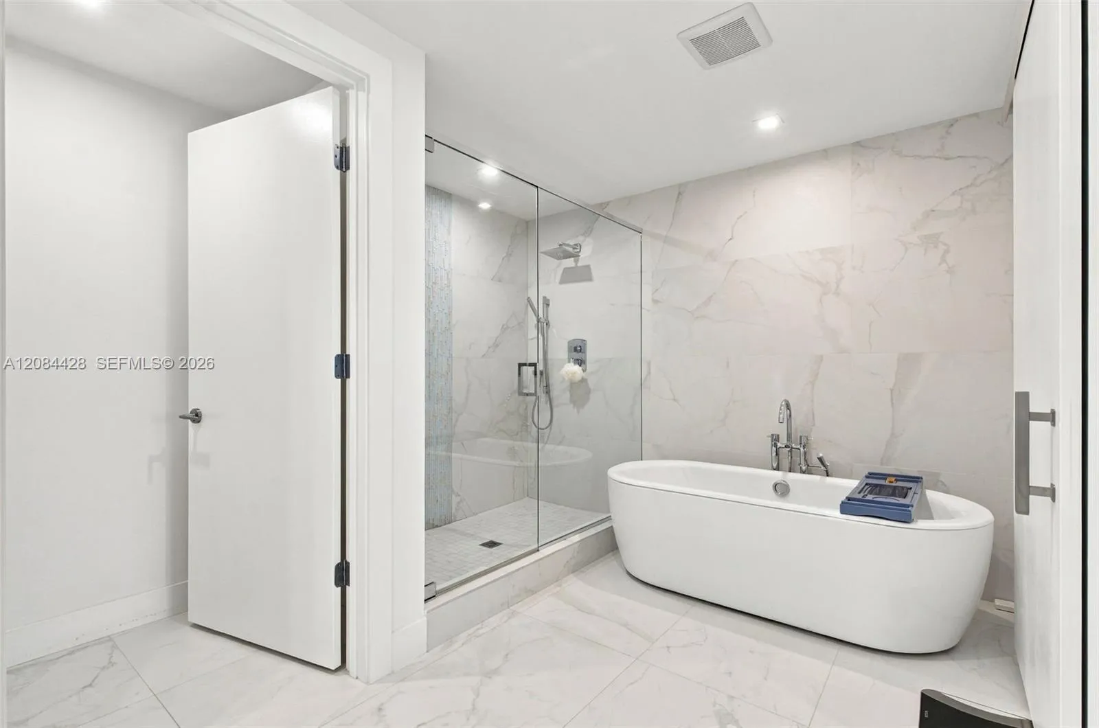 Spa-like primary bathroom with a freestanding soaking tub and glass-enclosed shower.