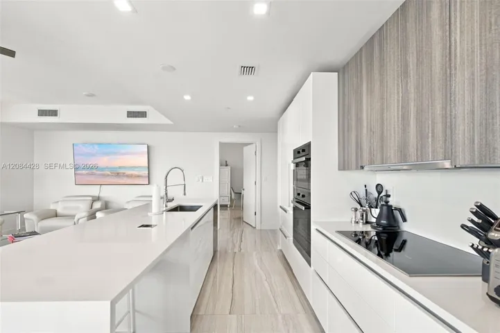 Sleek kitchen with extensive cabinetry, built-in appliances and separate cooktop.