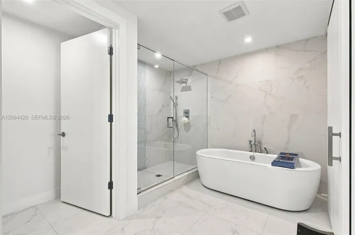 Spa-like primary bathroom with a freestanding soaking tub and glass-enclosed shower.