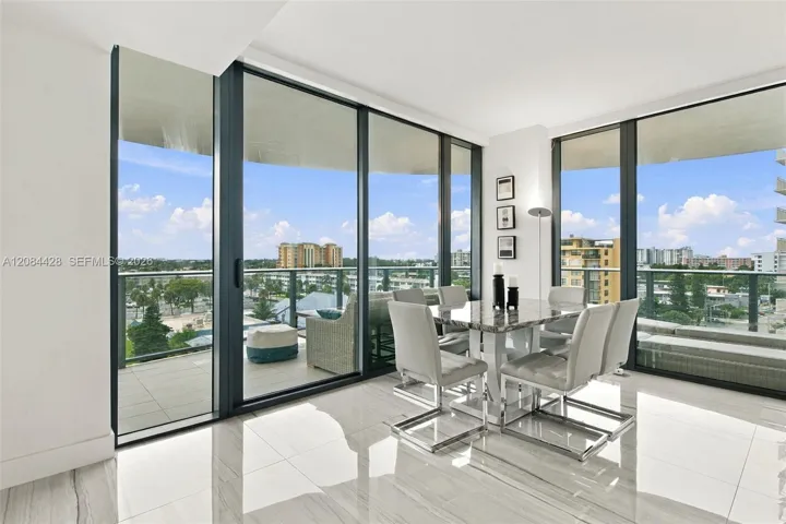 Bright dining area surrounded by floor-to-ceiling windows with direct balcony access.