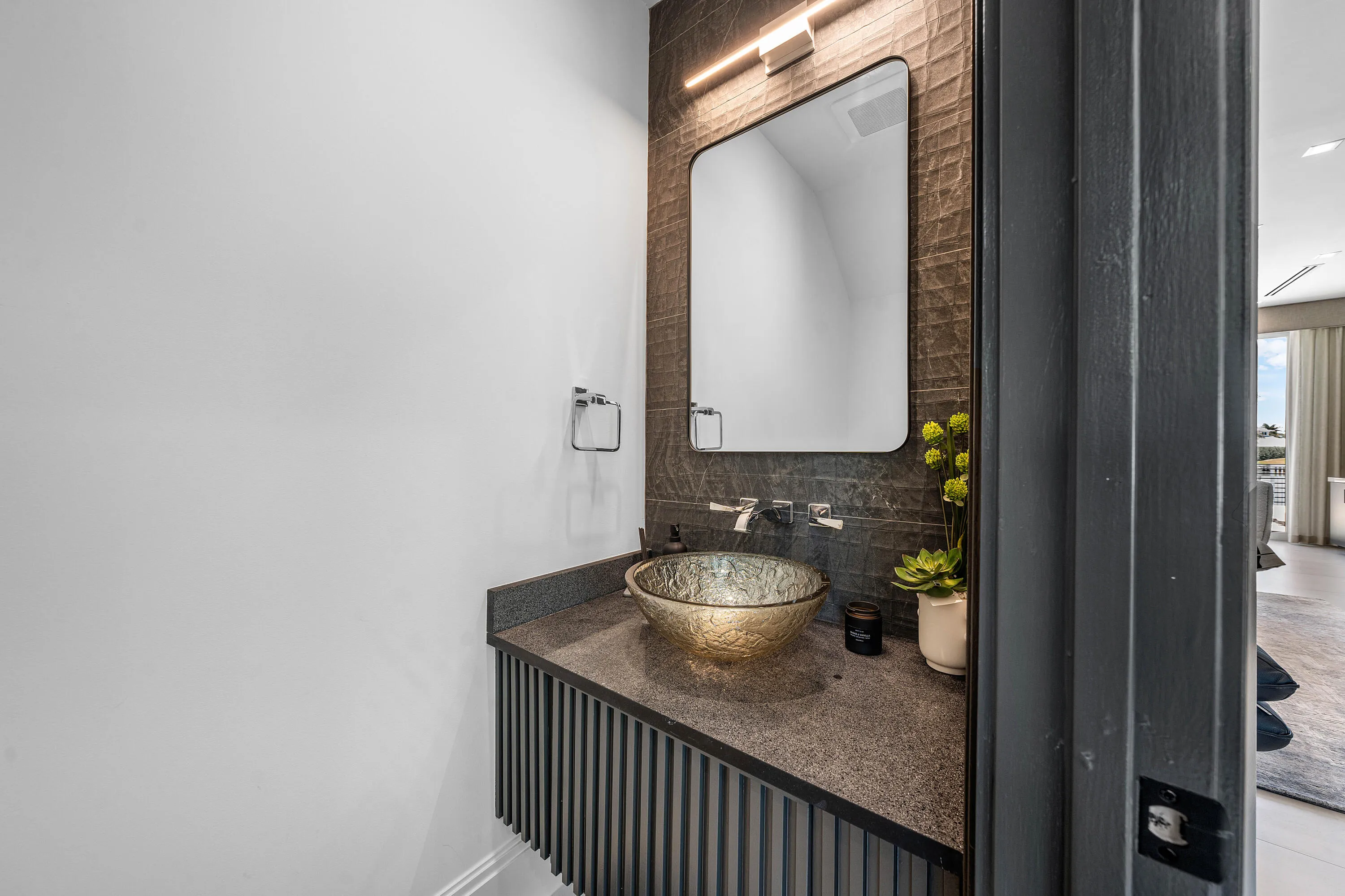 Floating vanity with a fluted wood-finish base, stone countertop, and glass vessel sink