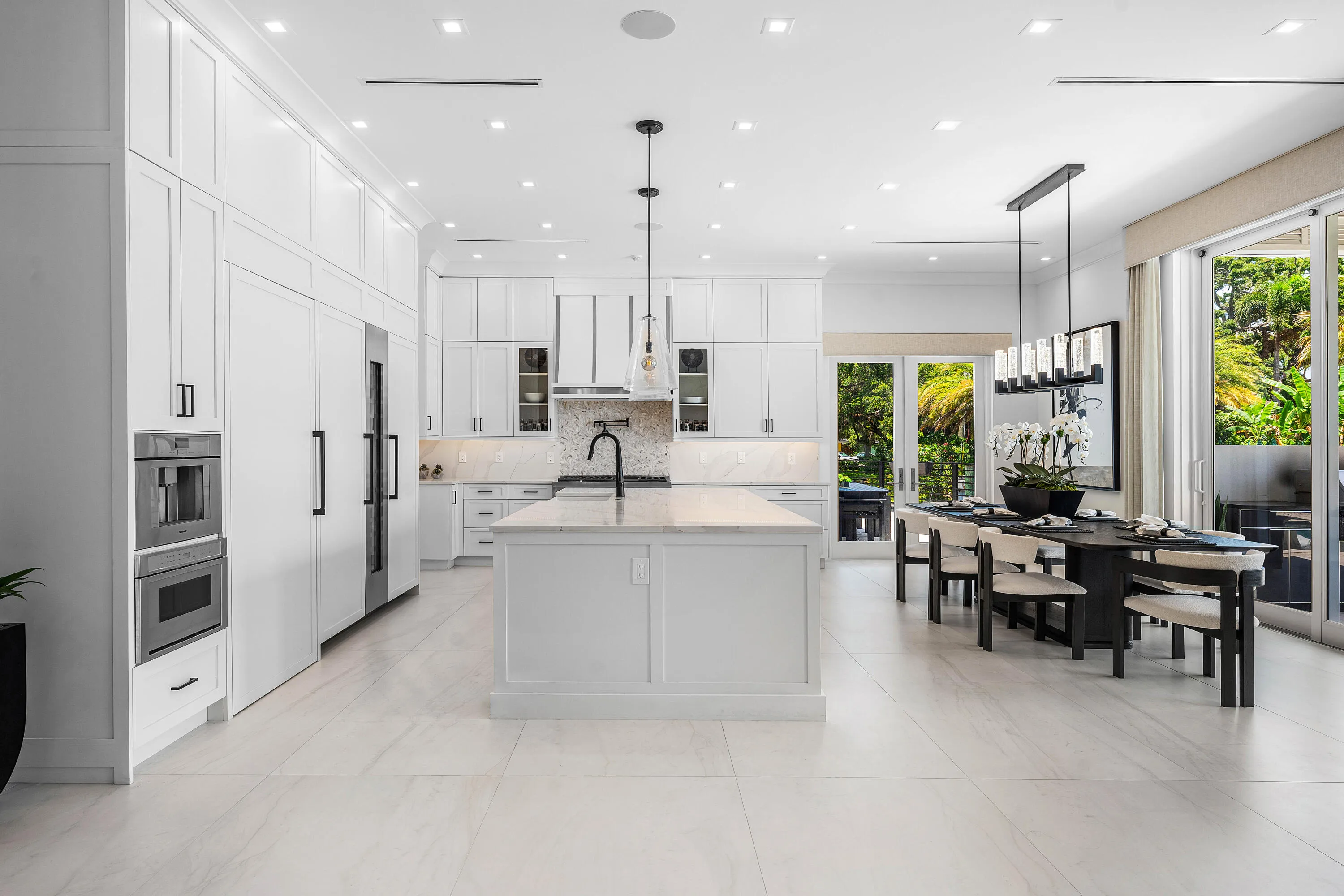 Gourmet kitchen featuring extensive white panel cabinetry, a large center island with countertop, integrated stainless steel appliances, and sleek tile flooring