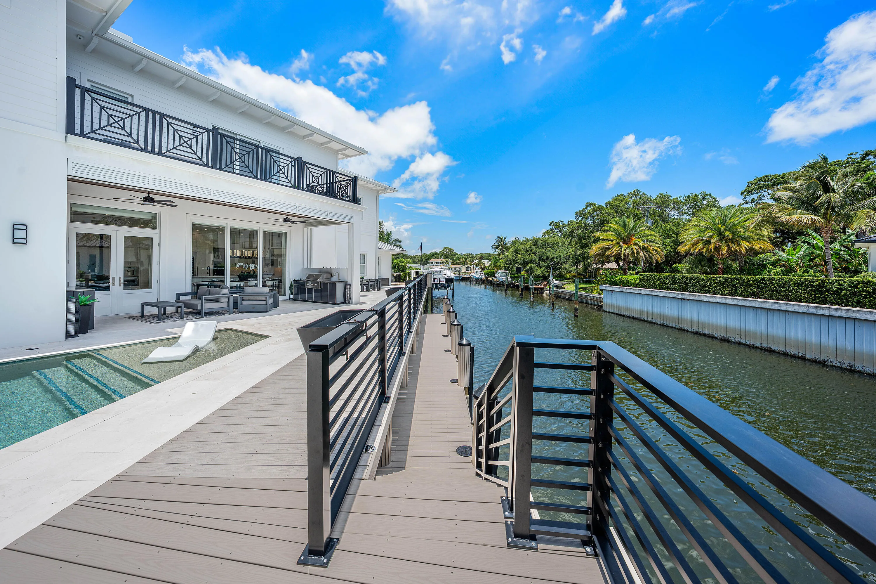 Waterfront property featuring a private dock with pilings, a boat lift, and a spacious deck with contemporary metal railings