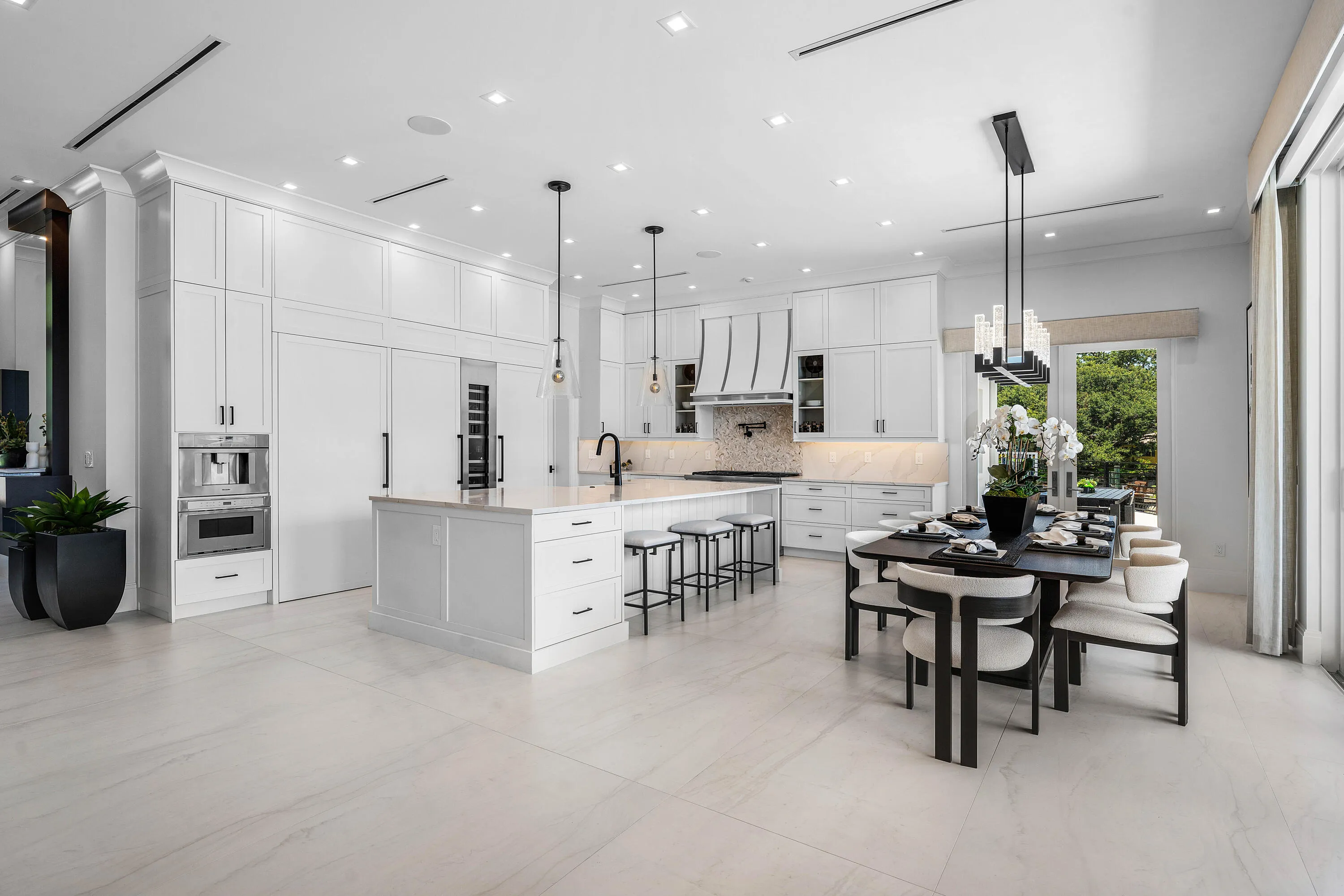 Spacious kitchen featuring white cabinetry, a large center island, and integrated appliances