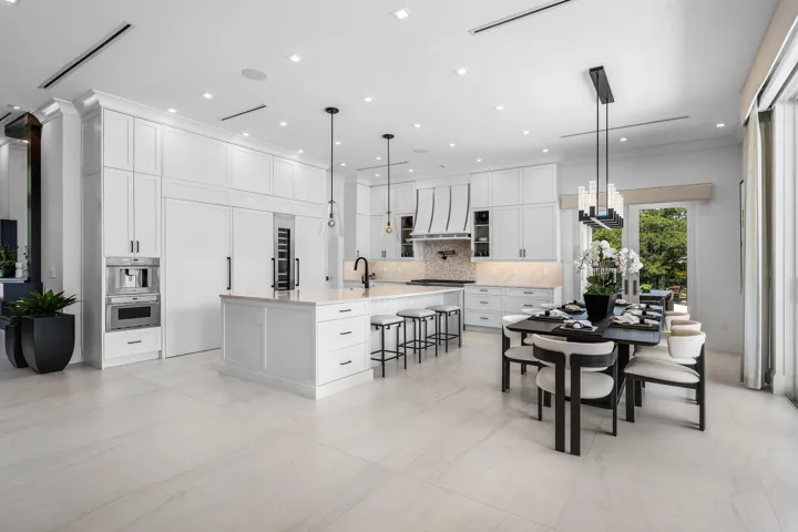 Spacious kitchen featuring white cabinetry, a large center island, and integrated appliances