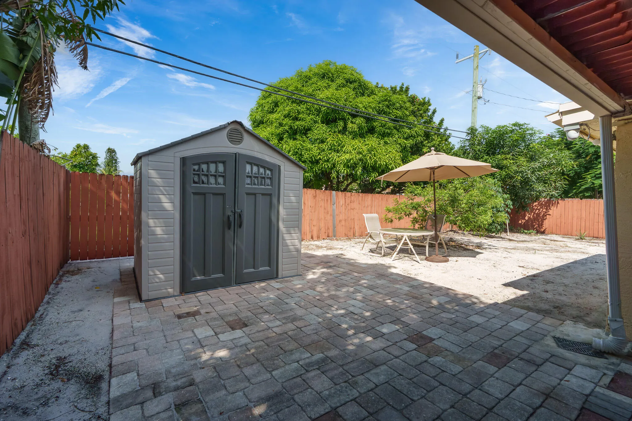 Paved area, privacy fencing, storage shed, and mature trees