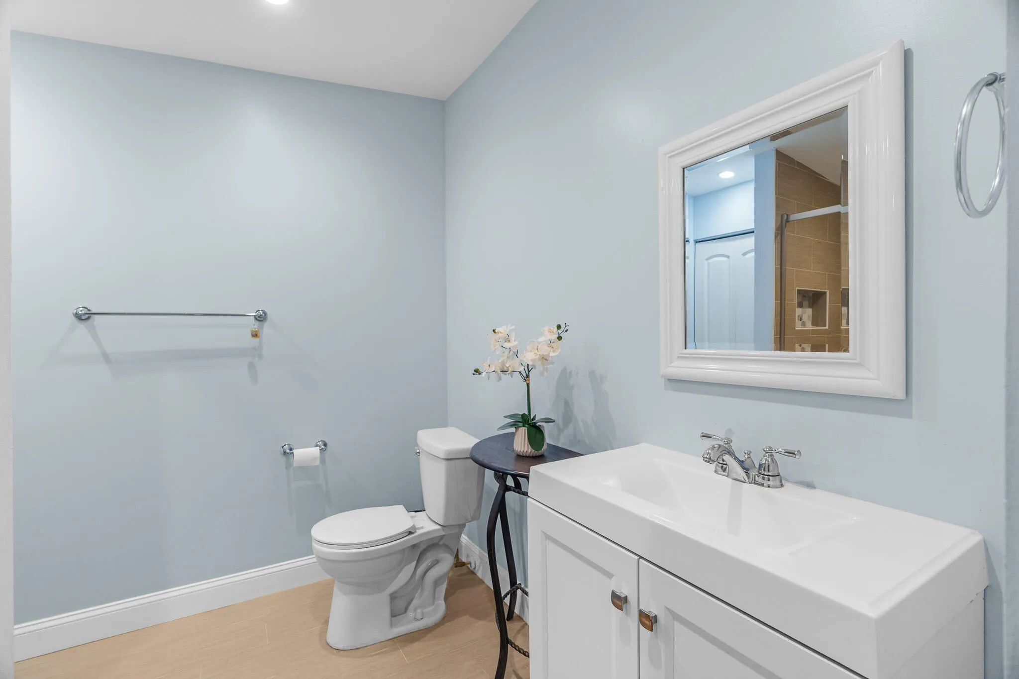 White vanity with integrated sink, chrome faucet, and framed wall mirror
