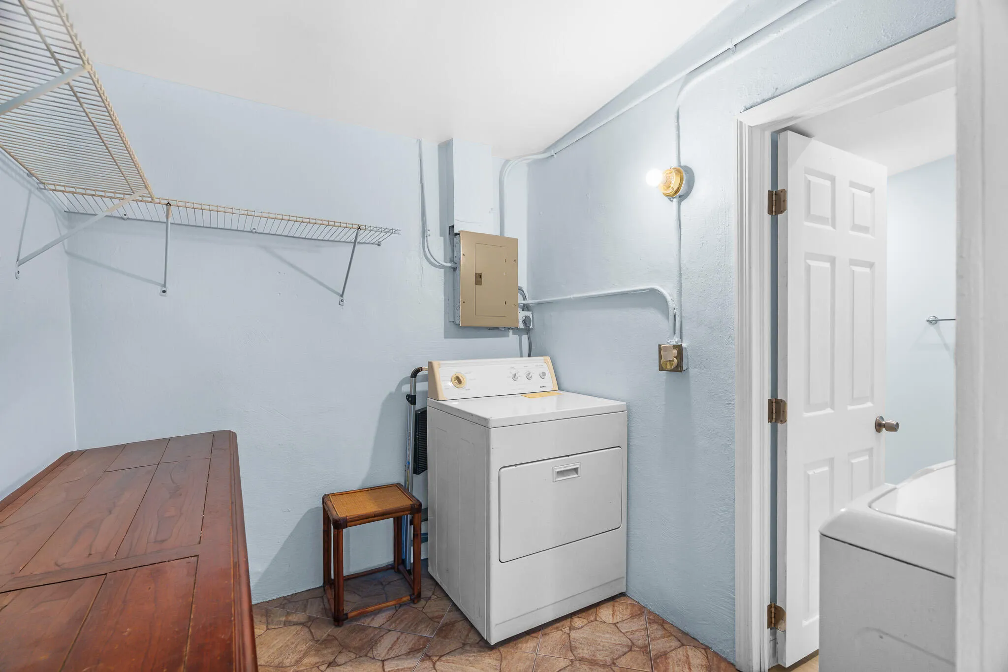 Laundry area featuring a utility sink, a built-in wire shelving unit, and stone-look flooring