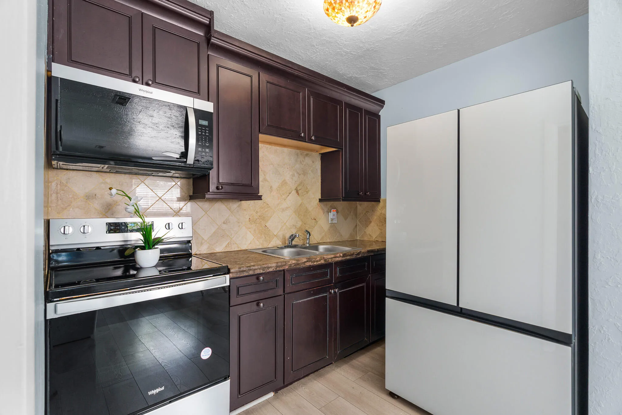 Wood-finish cabinetry paired with a tile backsplash and dark countertops