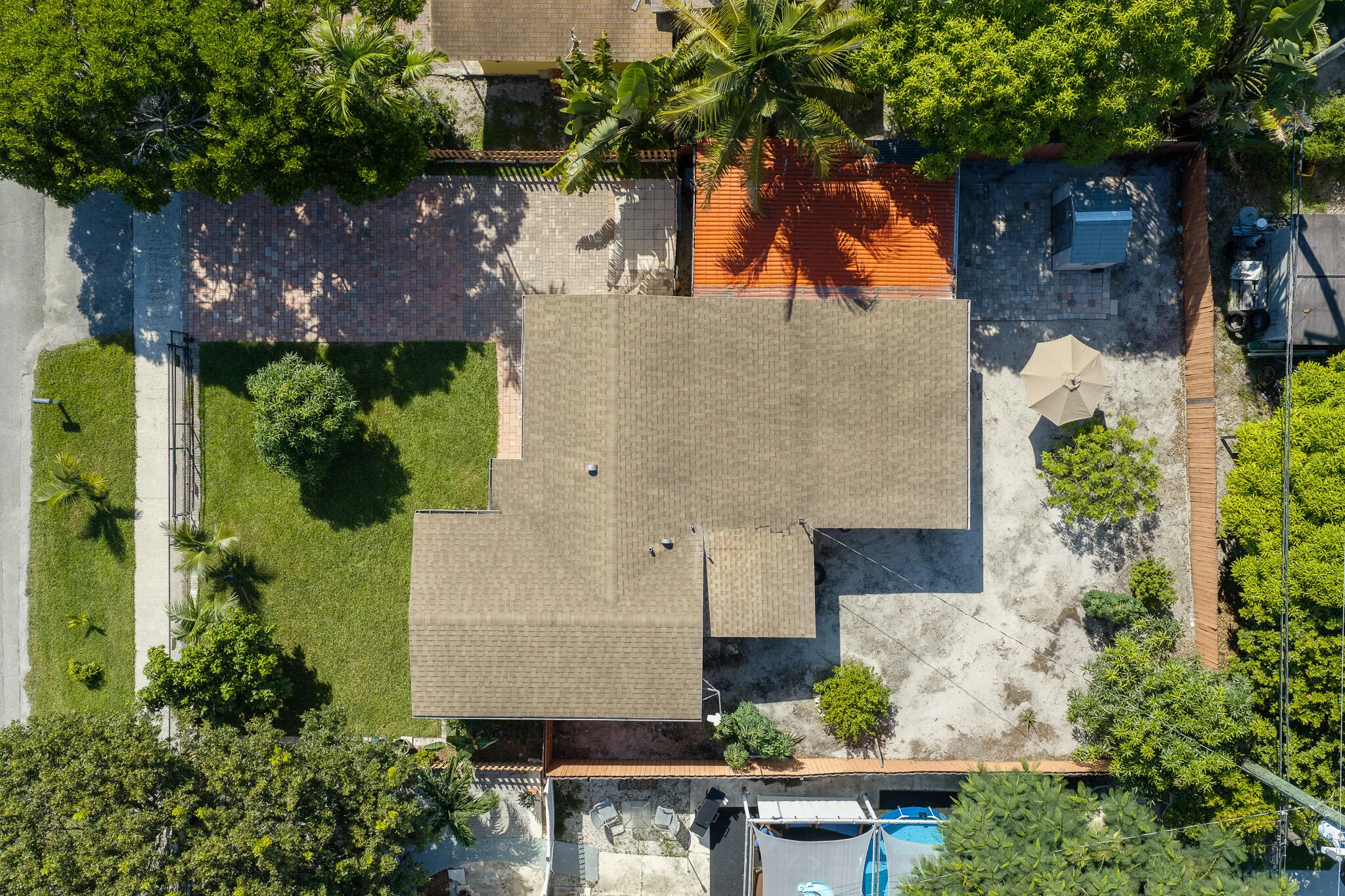 Expansive roofline, mature perimeter trees, front lawn, paved driveway, concrete rear patio