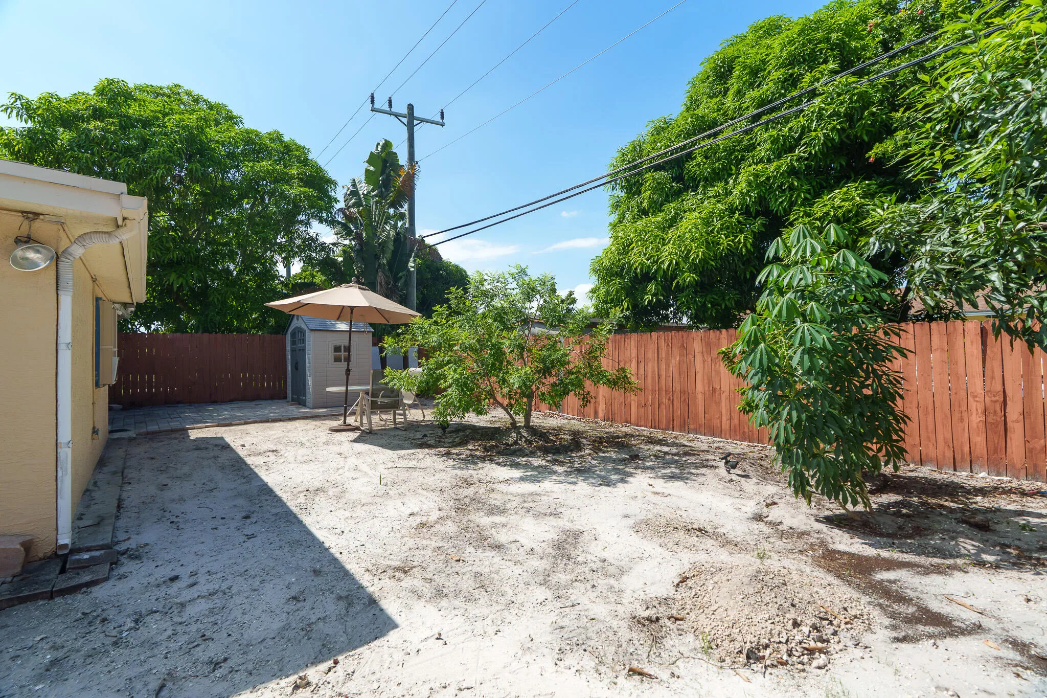 Private yard with a wood fence, mature perimeter trees, and a detached storage shed