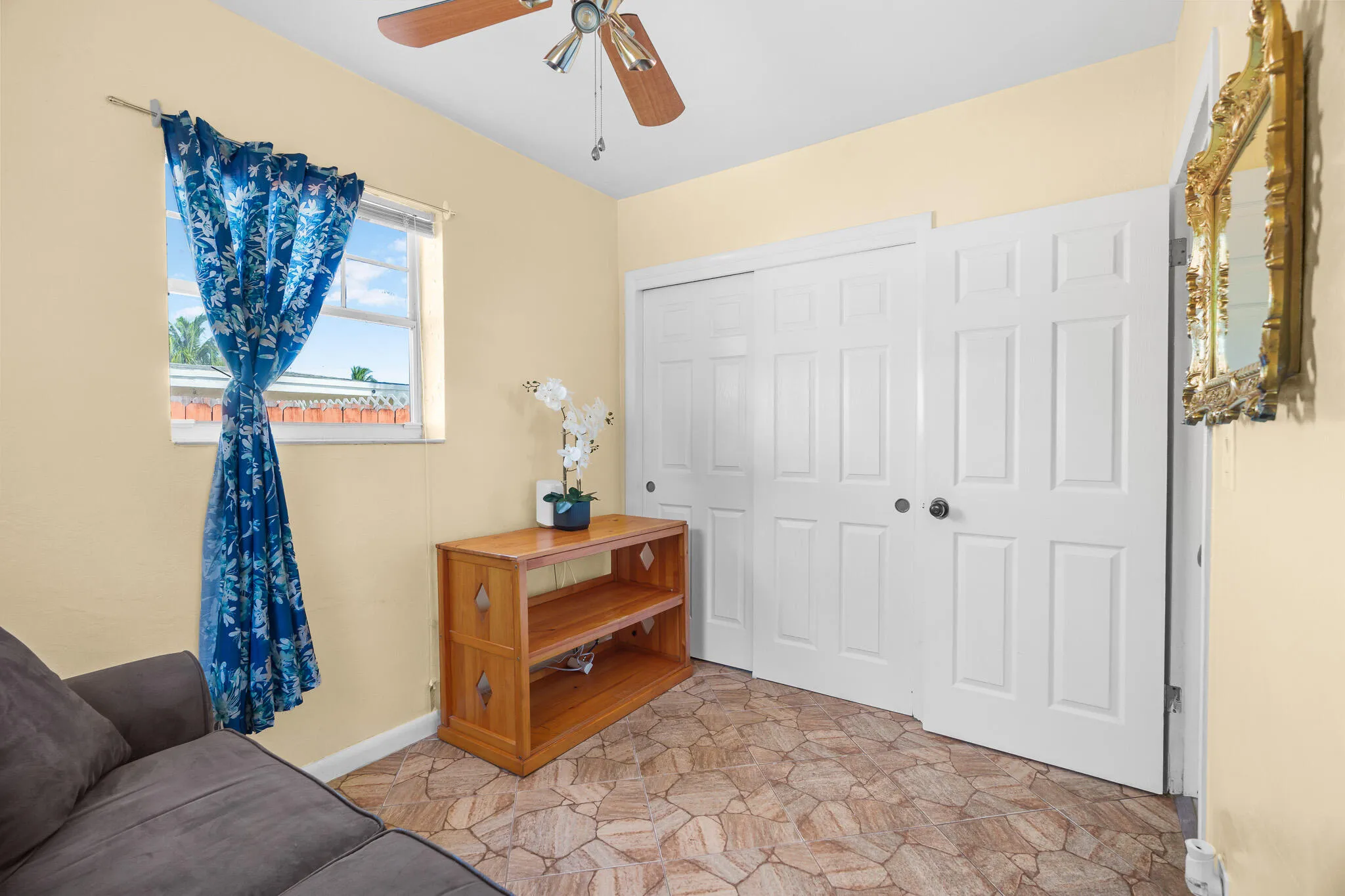 Room featuring a ceiling fan, window, paneled closet doors, and wood-finish flooring