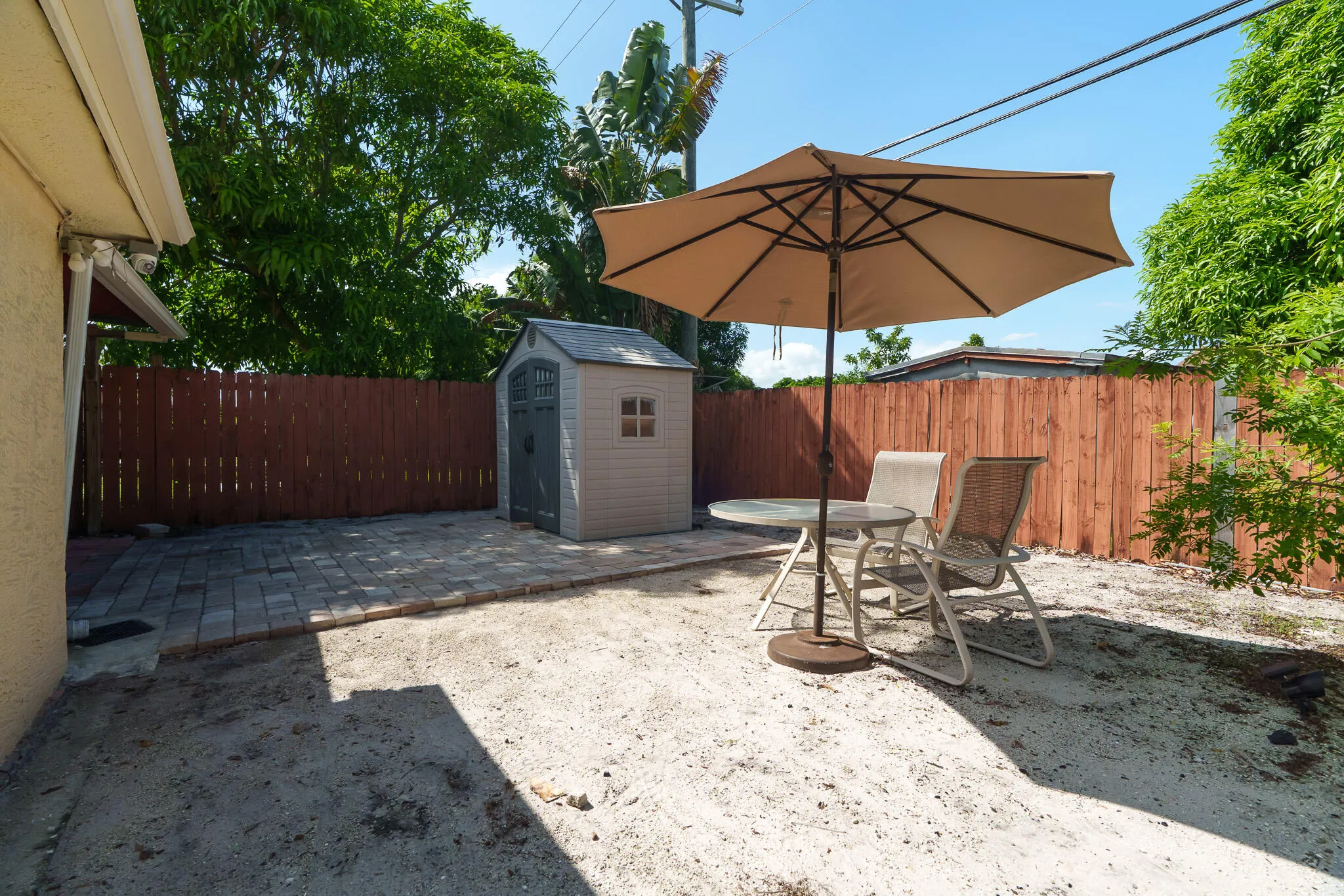 Enclosed backyard featuring a privacy fence, pavers, and storage shed