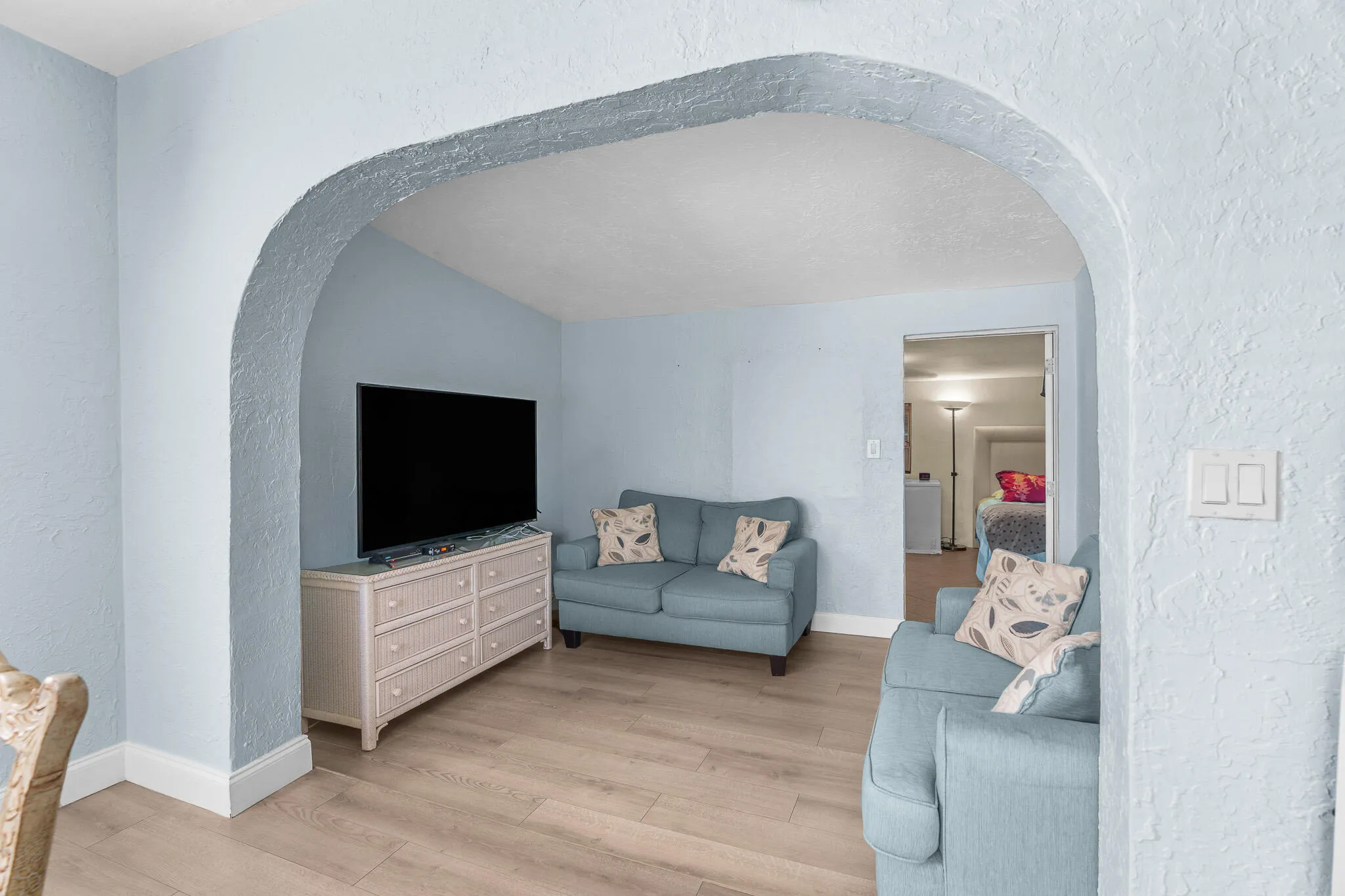 Archway entrance with textured finish, light wood-finish flooring, and white trim