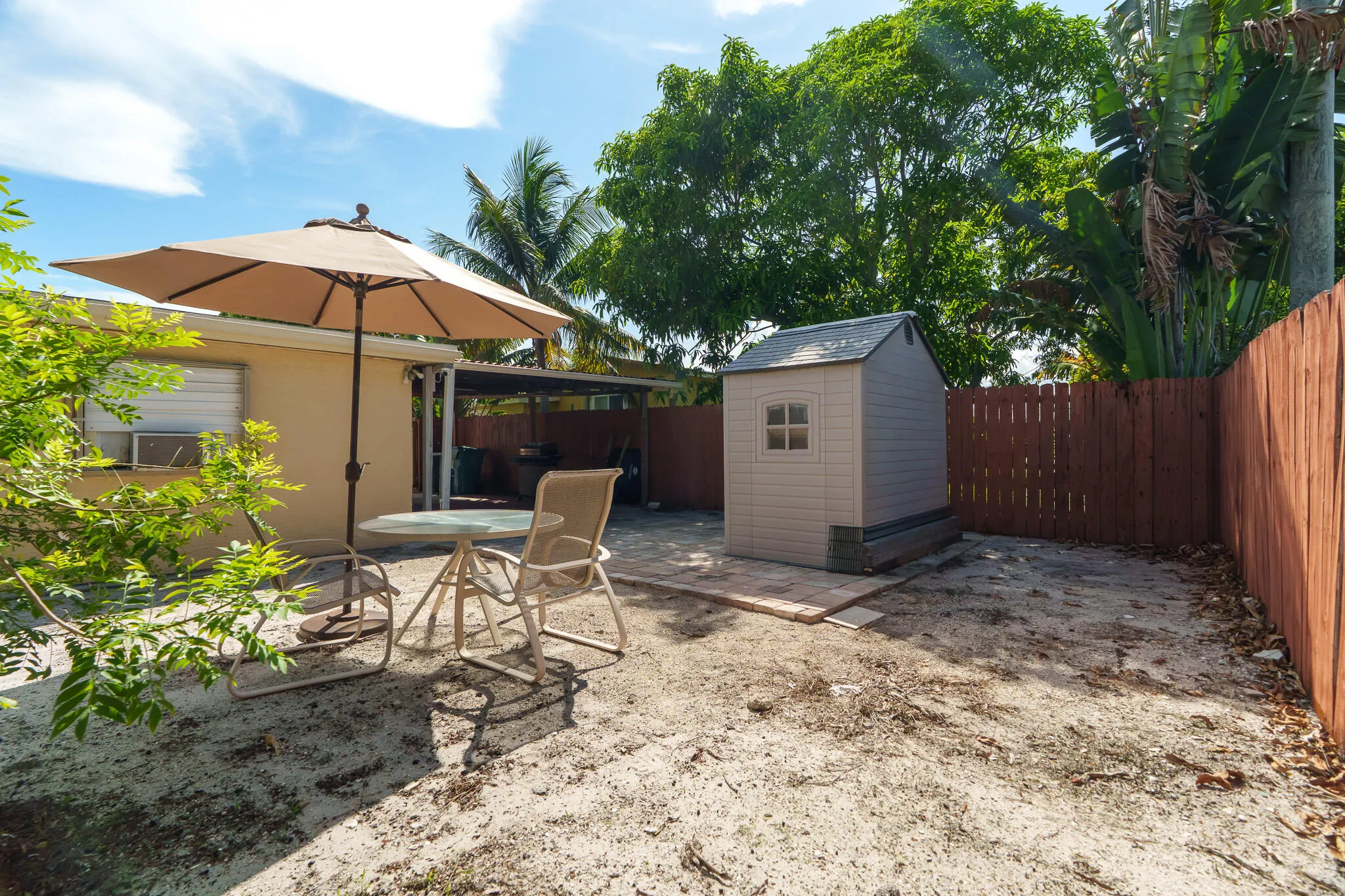 Enclosed backyard featuring a privacy fence, storage shed on a paver base, and a covered patio area