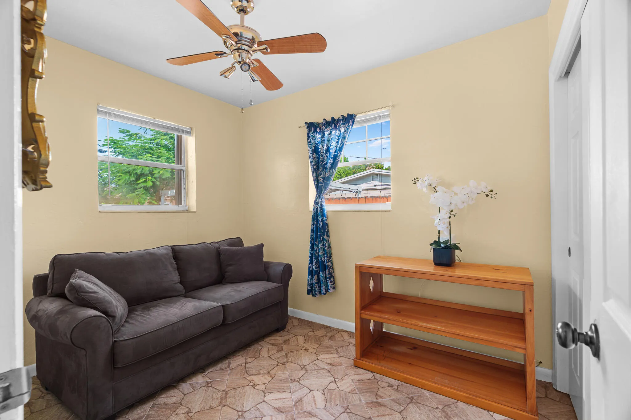 Ceiling fan, two windows, textured flooring, and a light-toned door