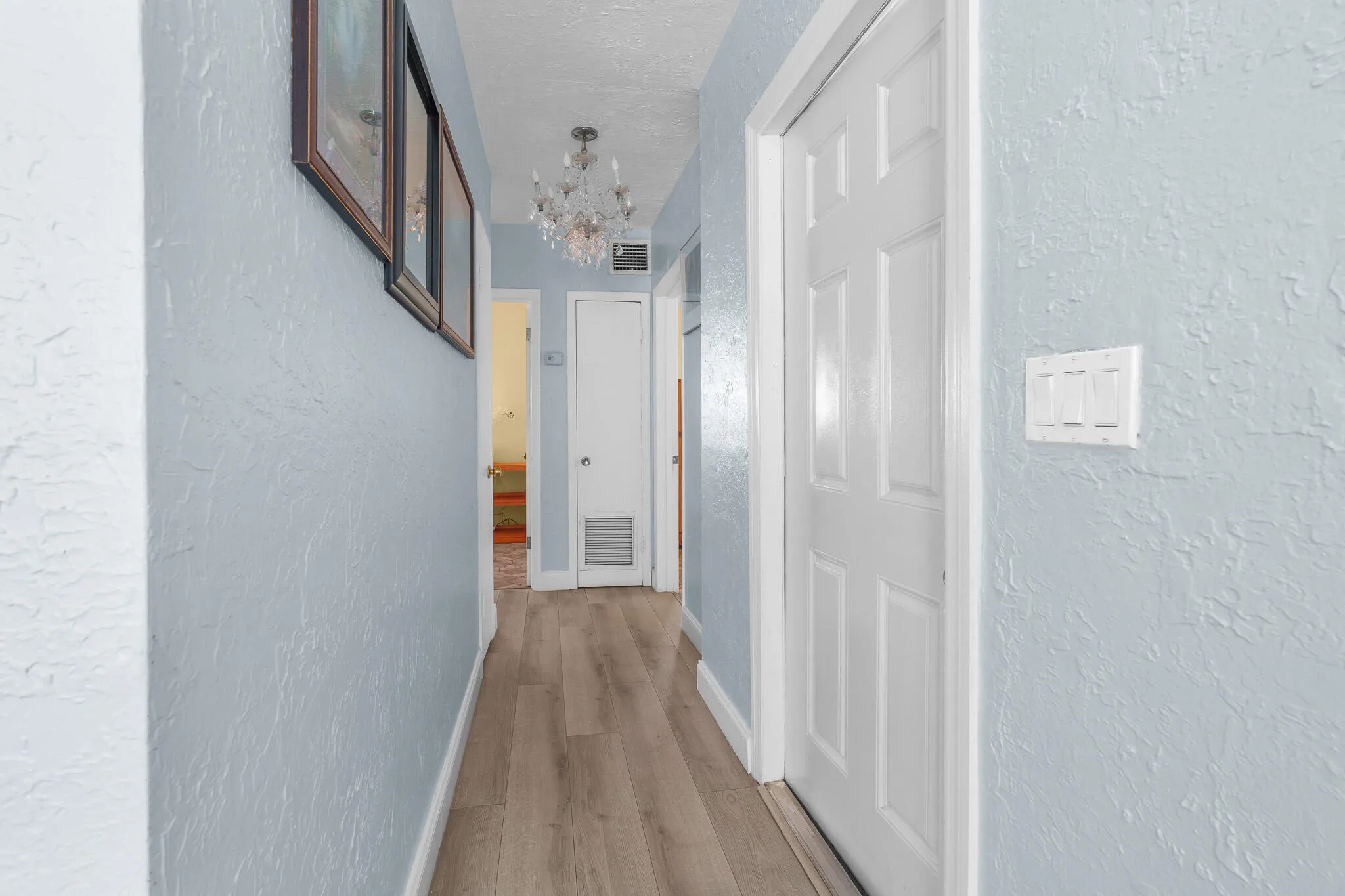 Wood-finish flooring throughout, complemented by a crystal chandelier and paneled interior doors
