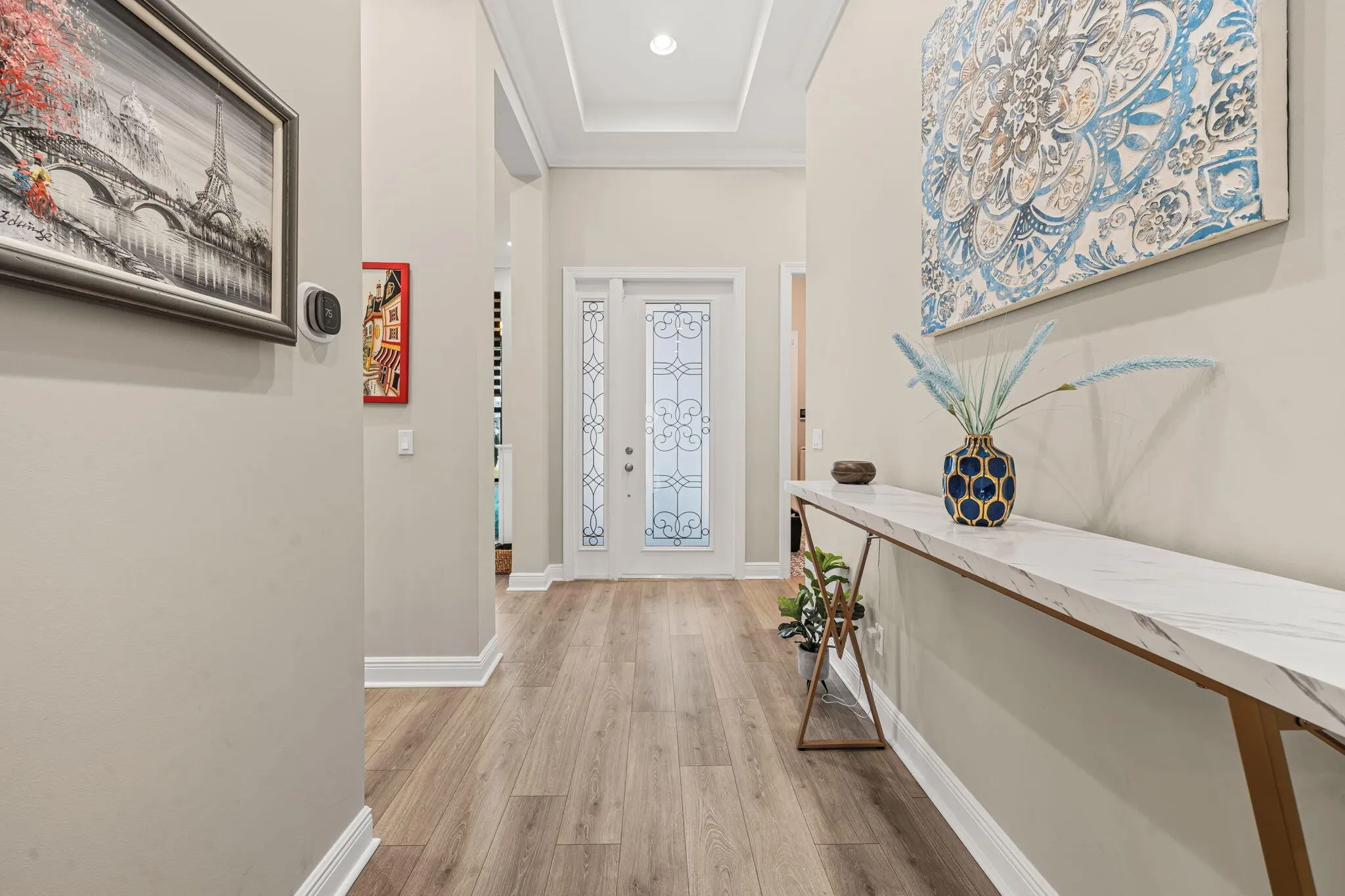 Foyer entry with wide plank wood-look tile flooring, decorative glass paneled door, transom window, and tray ceiling