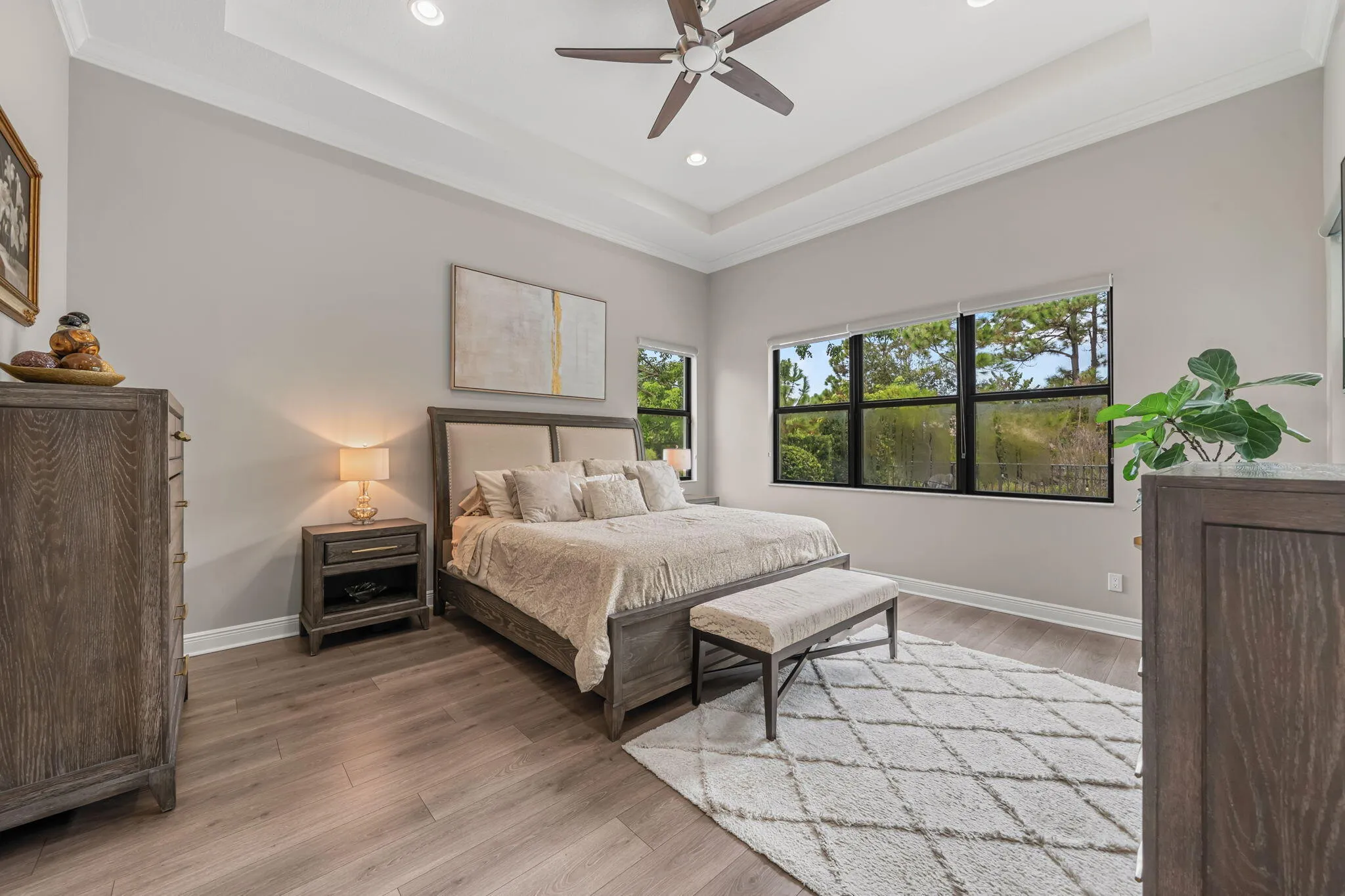 Bright and spacious primary suite with tray ceilings, recessed lighting and crown molding