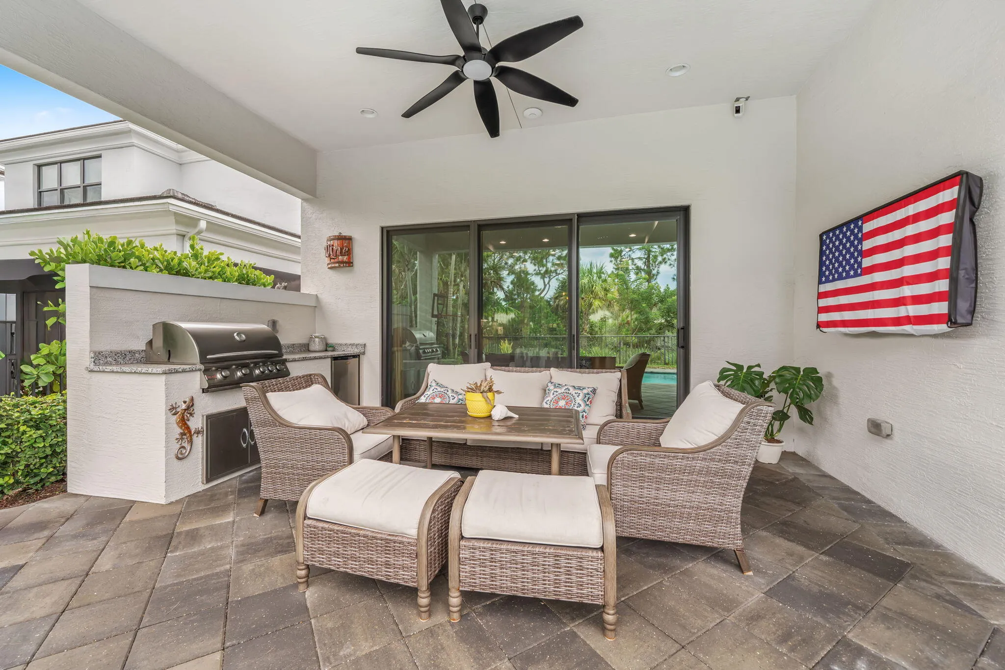 Covered patio featuring an outdoor kitchen with grill and built-in cabinetry, ceiling fan, and sliding glass doors