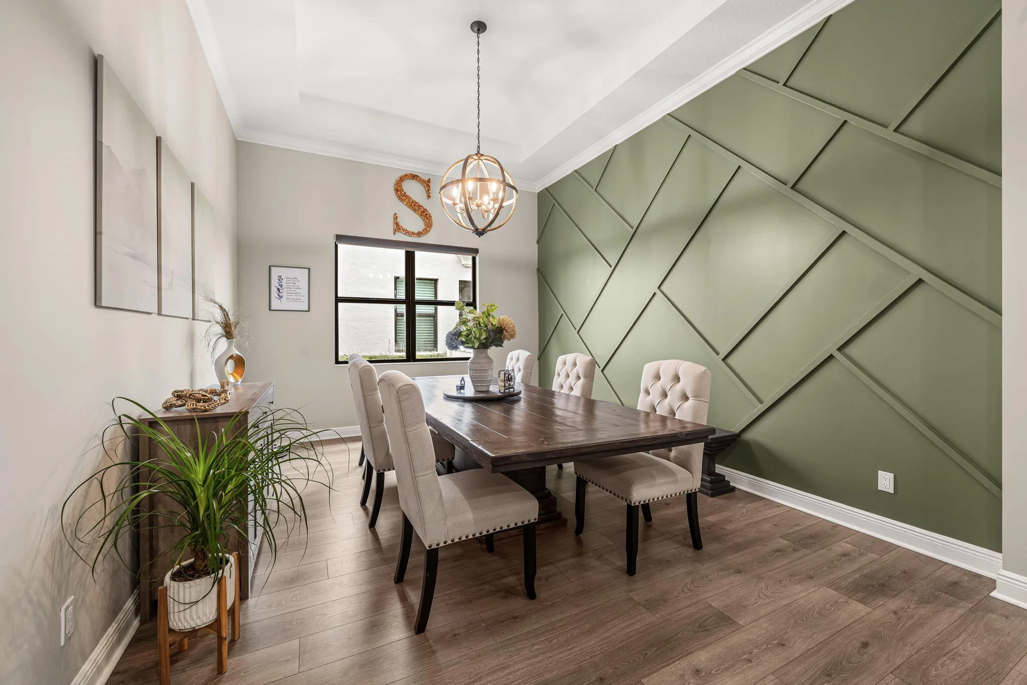 Tray ceiling with recessed lighting, accent wall with geometric paneling, large window, and suspended spherical chandelier