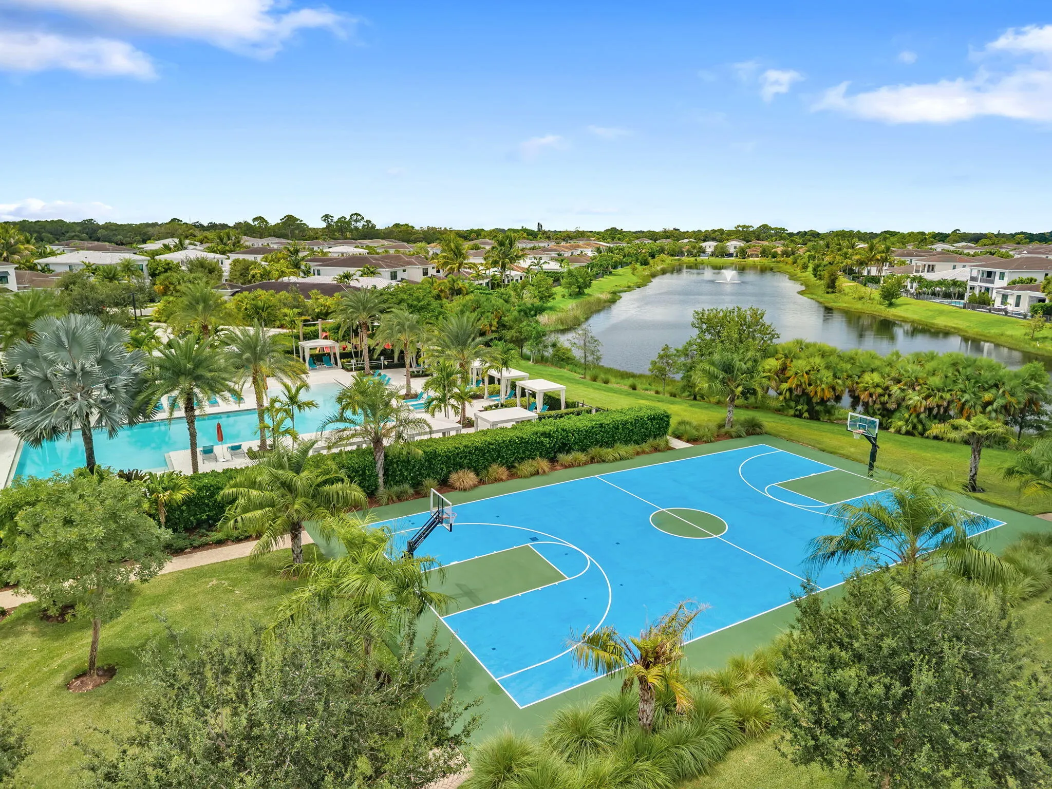 Outdoor basketball court, expansive swimming pool, lush landscaping, tranquil water feature, and surrounding residences