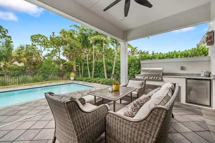 Covered patio with a built-in outdoor kitchen, stainless steel grill, and refrigerator