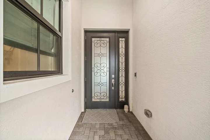 Patterned glass entry door with a sidelight, complementary window, and textured exterior finish