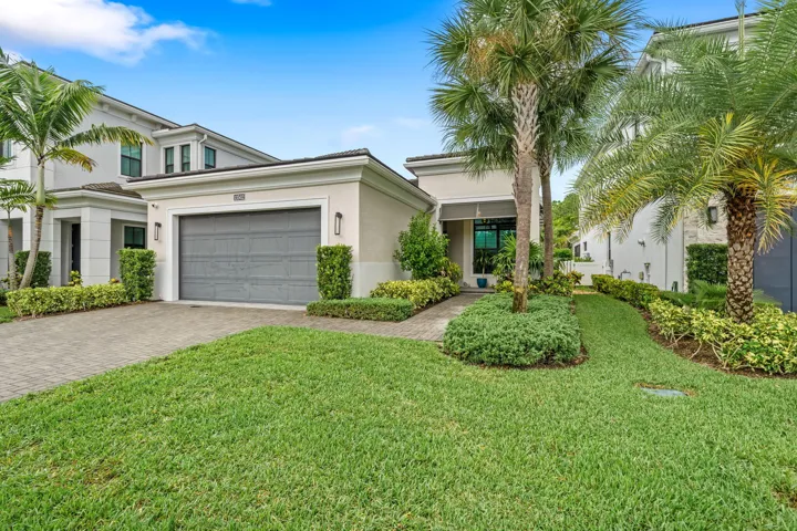 Contemporary exterior with a paver driveway, an attached garage, and mature landscaping.