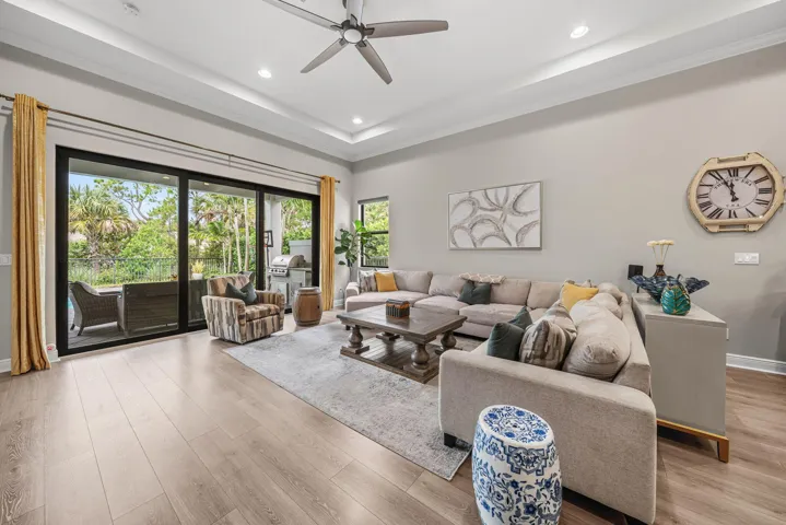 Spacious living area featuring, a tray ceiling with recessed lighting ceiling fan, and expansive sliding glass doors leading to an outdoor patio