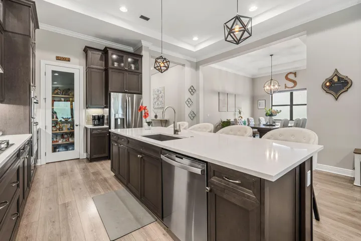 Kitchen featuring a large island with white Quartz countertops, dark wood cabinetry, stainless steel appliances, and wide plank wood-look tile flooring