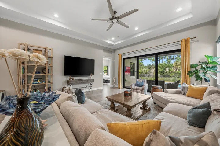 Spacious living area featuring a tray ceiling, recessed lighting and a large sliding glass door