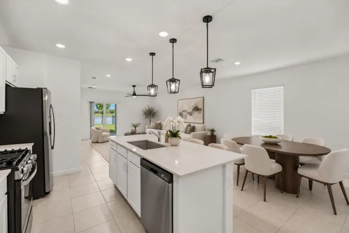 Kitchen featuring a central island with an undermount sink, pendant lighting, stainless steel appliances, and tile flooring