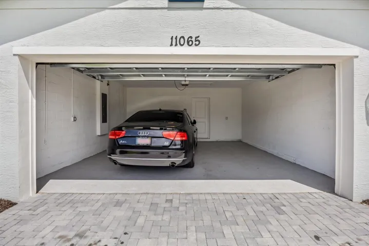 Attached two-car garage with a finished floor, interior access door, and a paver driveway
